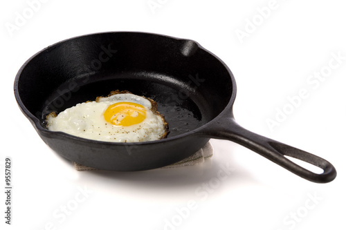 A fried egg in a black iron skillet on a white background
