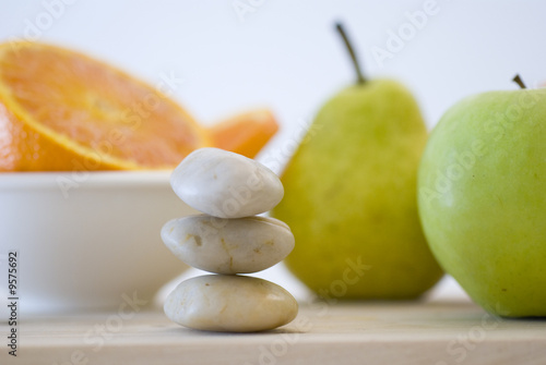 zen stones and orange, apple, pear fruits on background