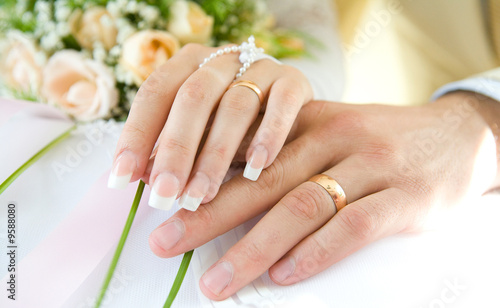 Ring & hands over white and flowers, wedding day