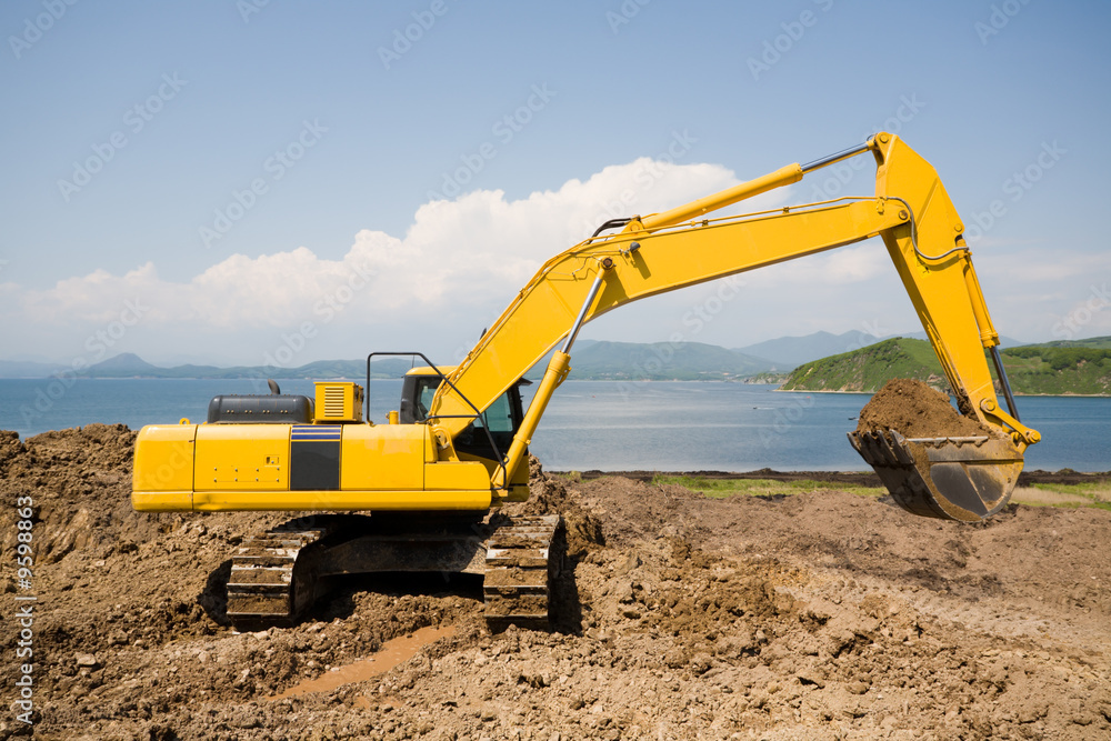 Excavator on the workplace on a background of the sea. Excavator on the workplace on a background of the sea.