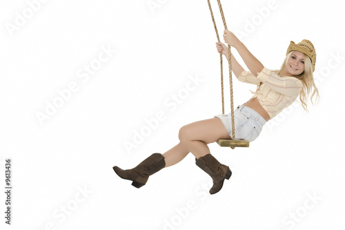 Caucasian cowgirl in wooden swing on white background