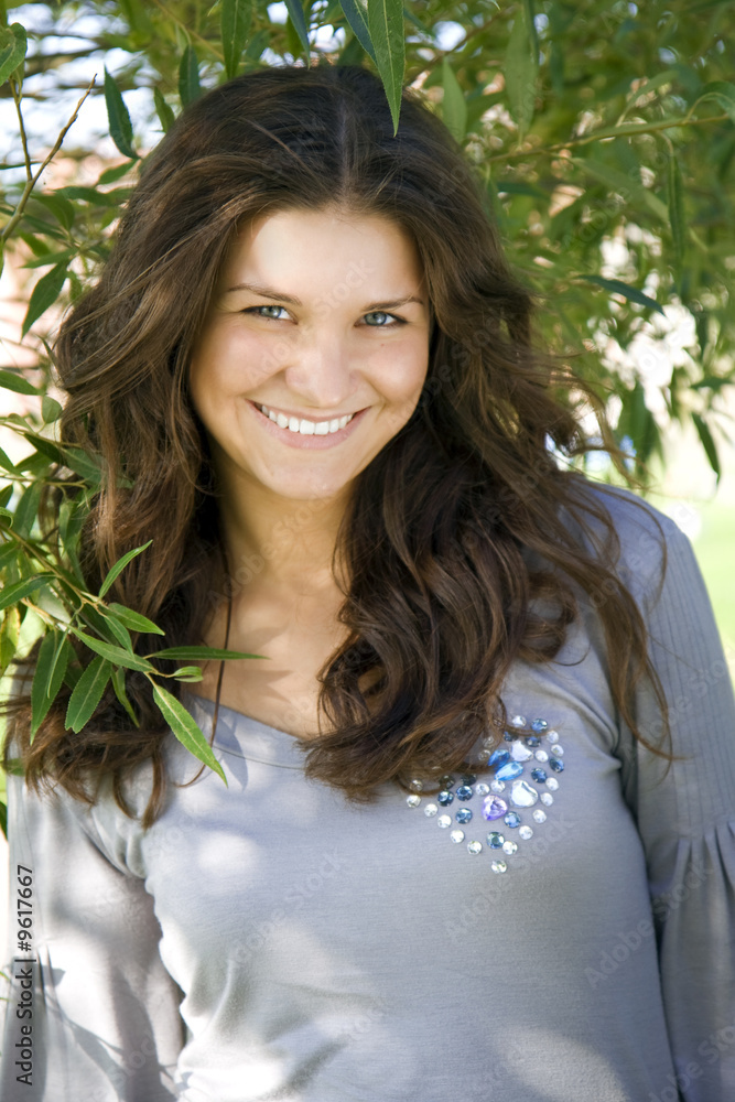beautiful smiling girl against a backdrop of green branches beautiful smiling girl against a backdrop of green branches