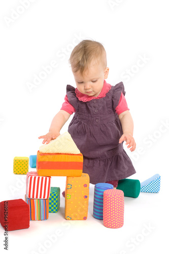 Little baby girl (9 months old) playing with toy blocks.
