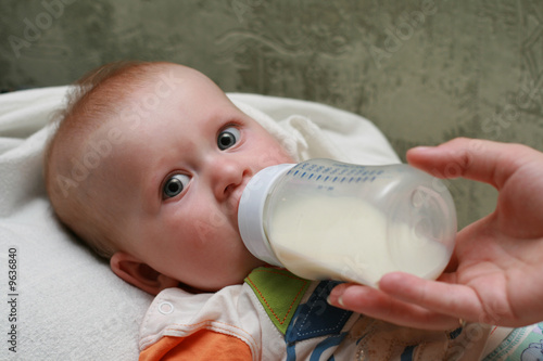 The little boy drinking milk from a bottle
