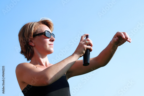 Femme vaporise de la crème solaire