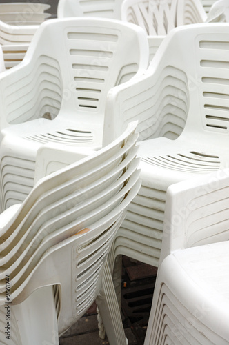 Stack of white plastic chairs on the street