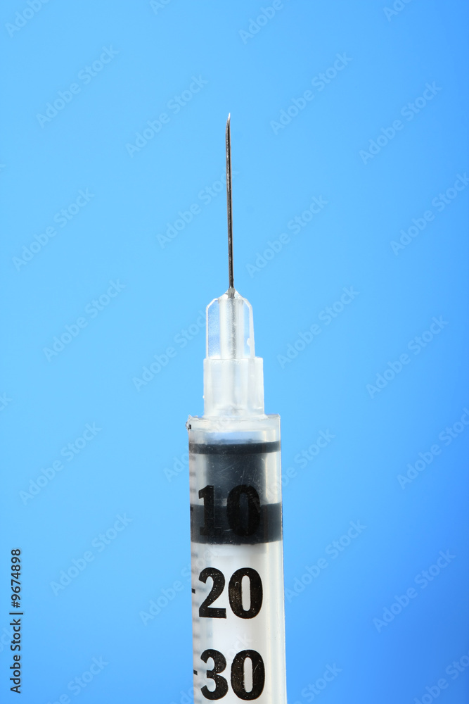 Vertical Hypodermic Needle, against soft blue background Vertical Hypodermic Needle, against soft blue background
