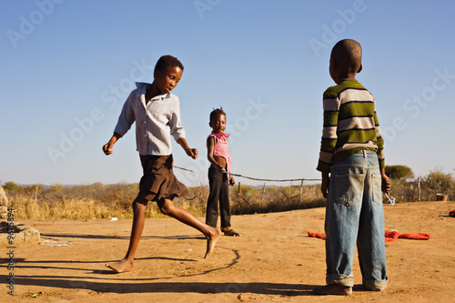 african children jumping rope in the sand,