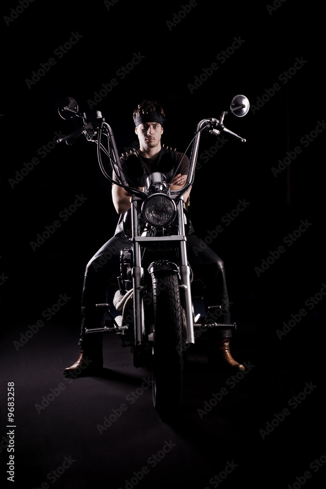Biker on chopper motorcycle in dark. Strong light from side