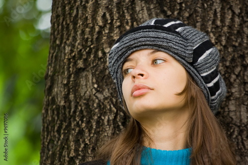 Portrait of a beautiful woman with hat standing near an old tree