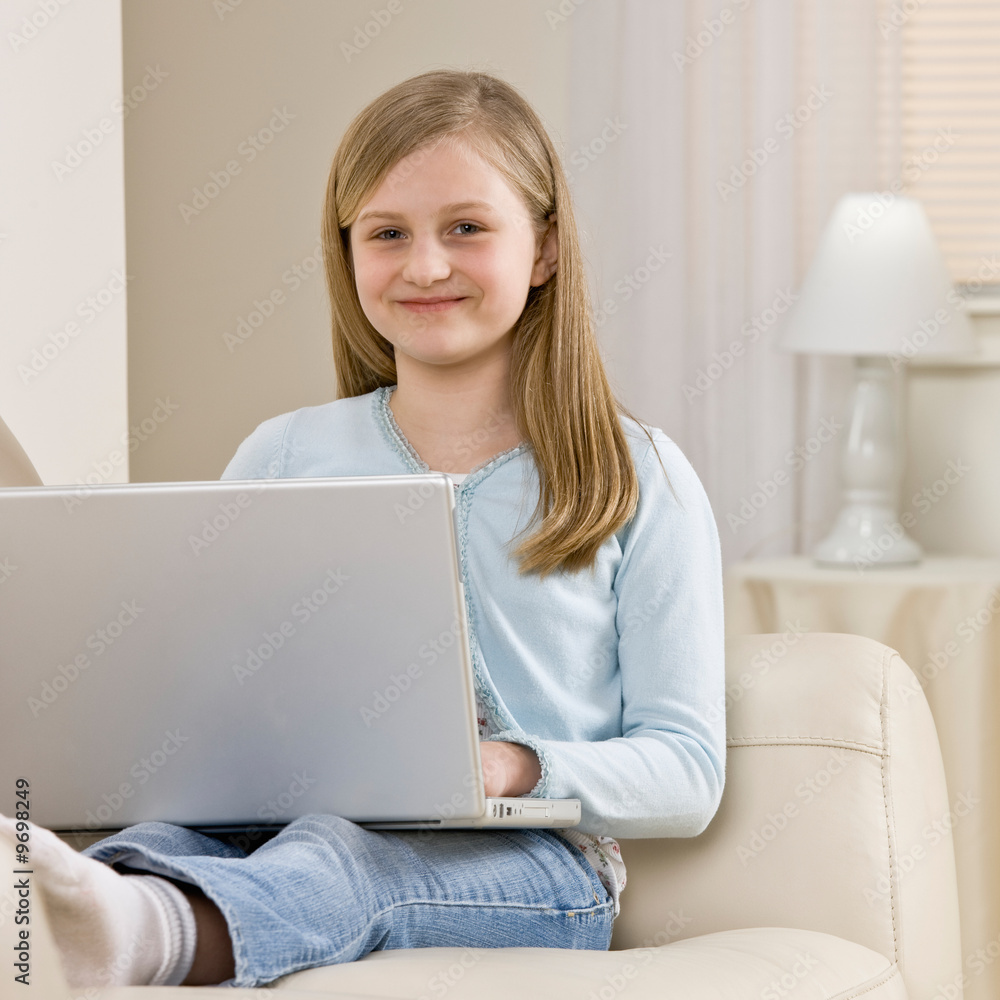 Girl relaxing on sofa in livingroom while typing on laptop Girl relaxing on sofa in livingroom while typing on laptop