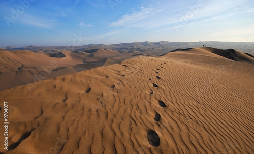 man waliking in a huge sand dune