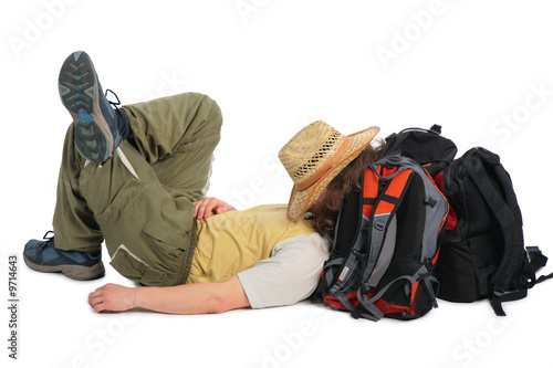 Traveller in straw hat lies on backpack and sleeps