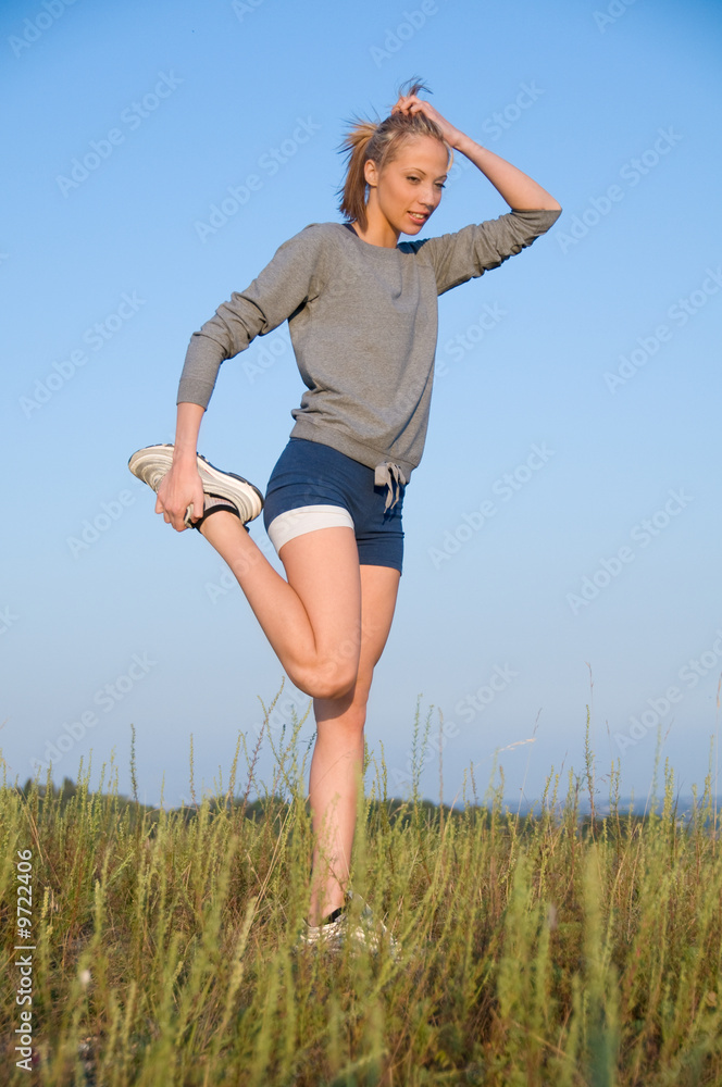 Athletics young woman stretching in a hilly meadow Athletics young woman stretching in a hilly meadow