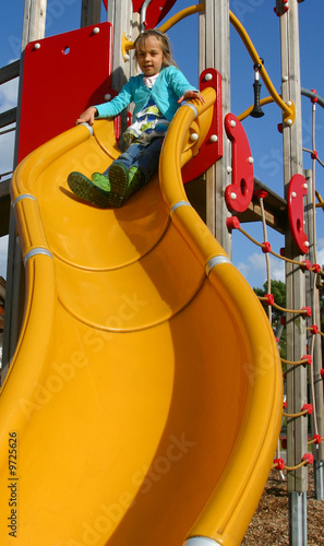 petite fille sur le toboggan jaune de l'aire de jeux