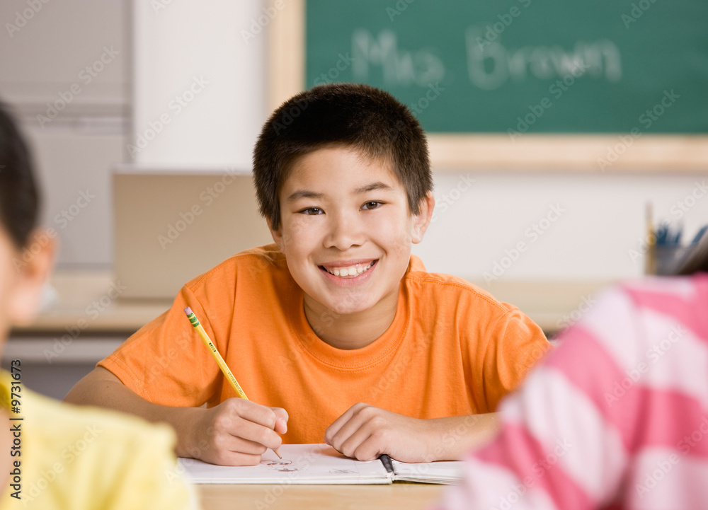 Happy student writing in notebook in school classroom Happy student writing in notebook in school classroom