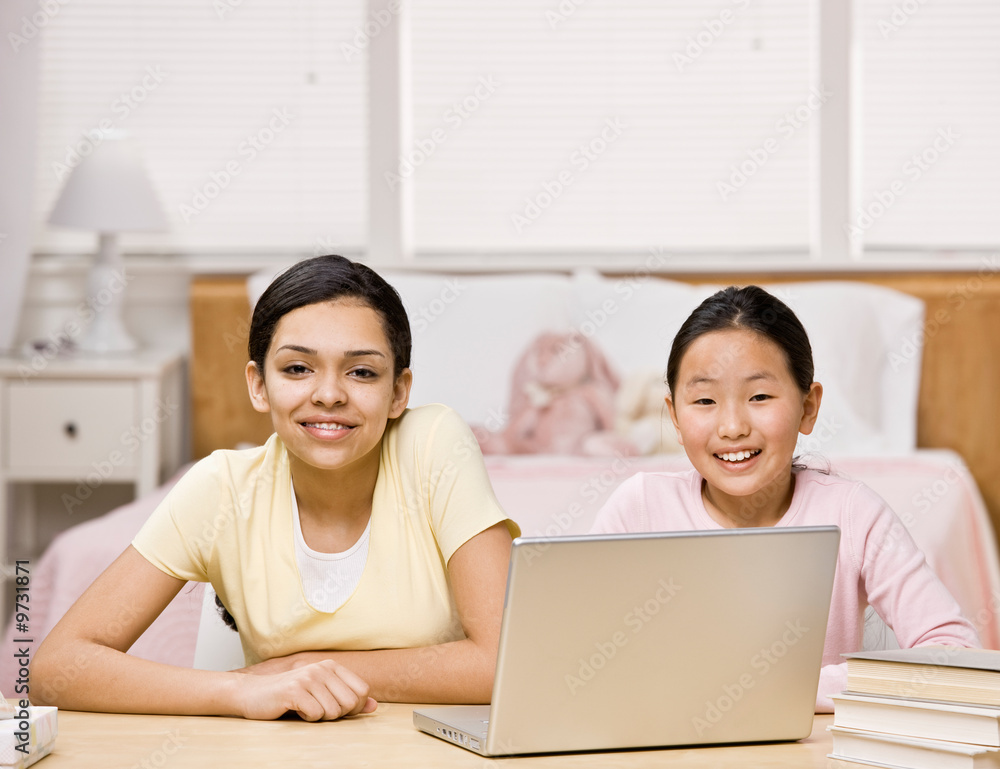 Happy, confident friends using laptop in bedroom Happy, confident friends using laptop in bedroom