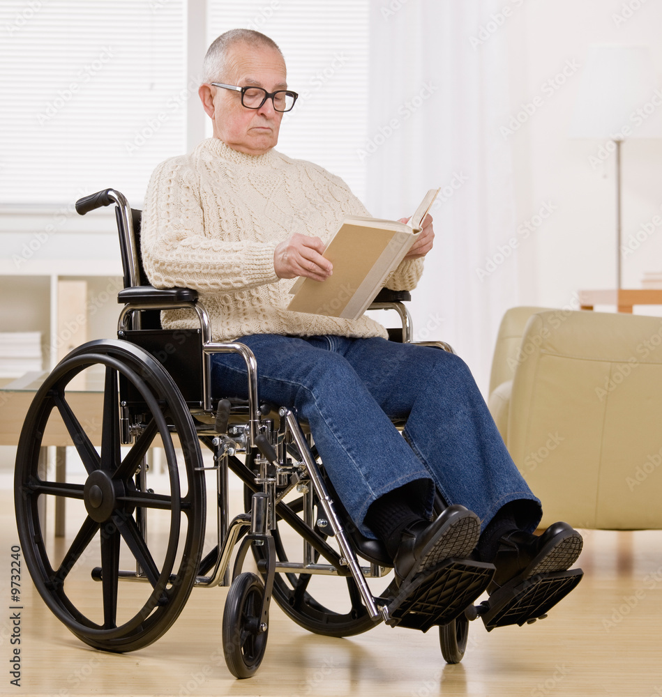Disabled man in wheelchair enjoying reading a book Disabled man in wheelchair enjoying reading a book