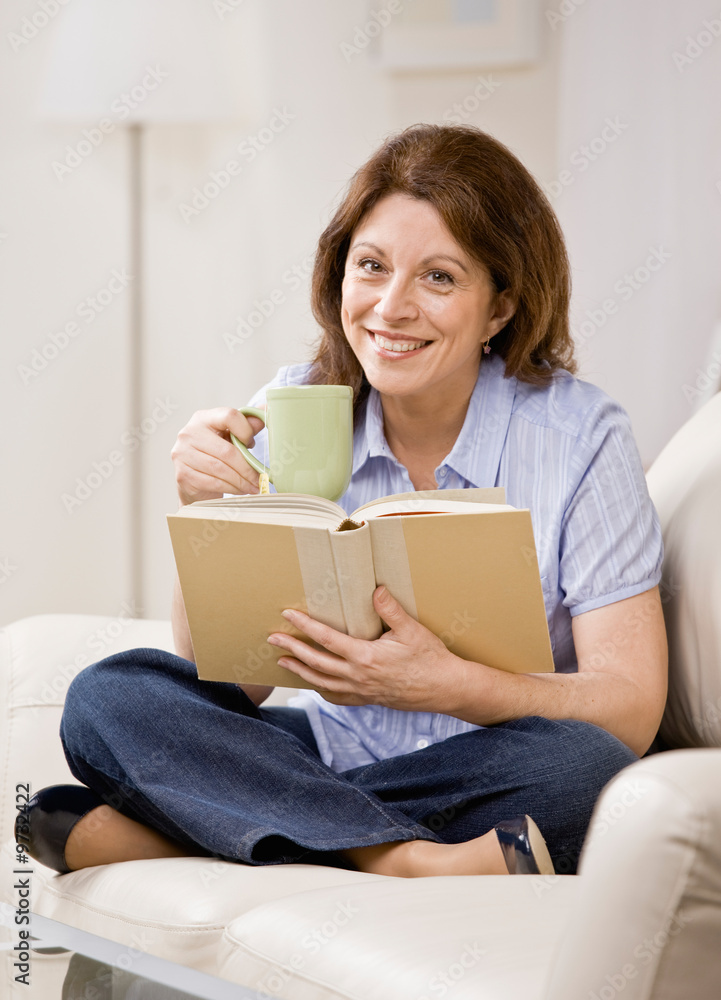Woman sitting on sofa in livingroom enjoying reading book Woman sitting on sofa in livingroom enjoying reading book