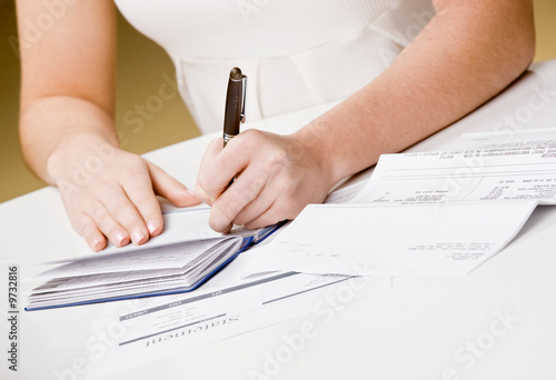 Woman writing checks from checkbook to pay monthly bills photo