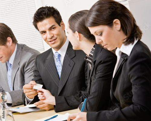 Woman handing co-worker business card in meeting