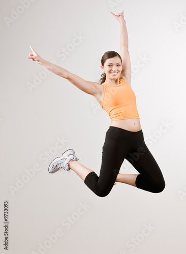 Strong athletic woman in sportswear excitedly jumping in mid-air