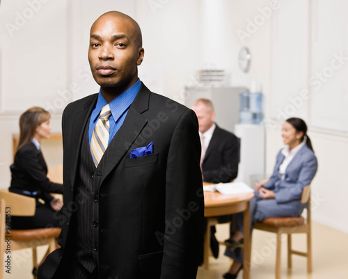 Confident businessman with co-workers in background