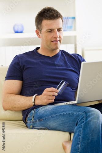 Man shopping online from home using credit card and laptop.