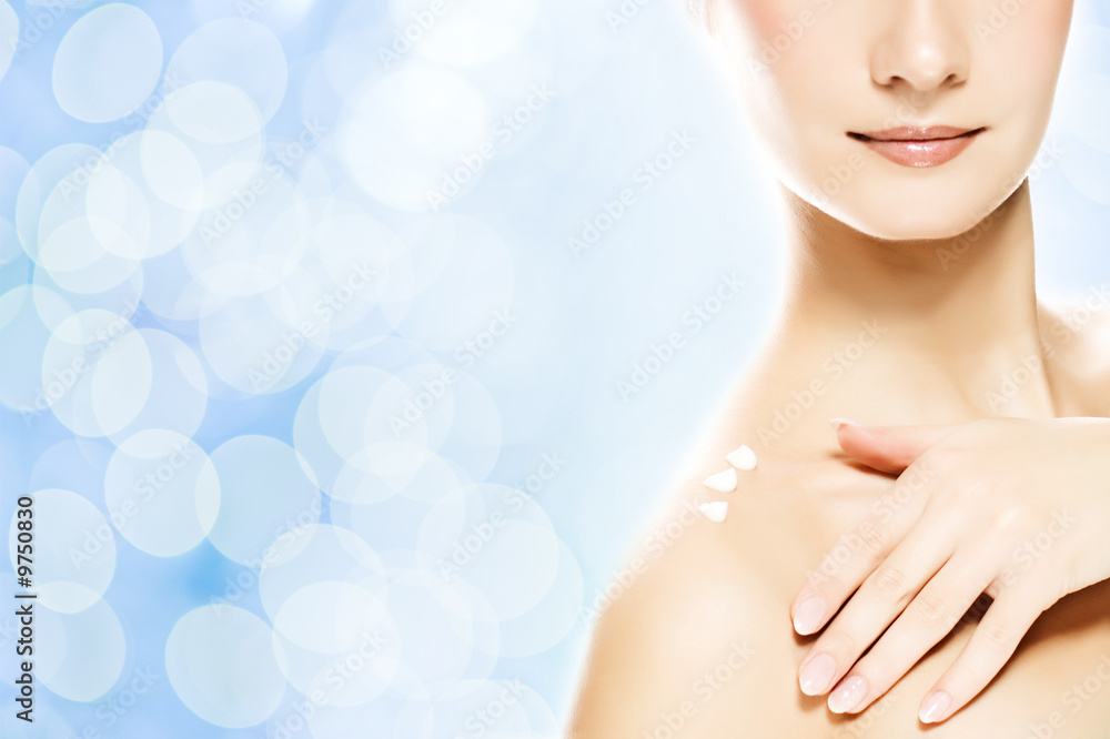 Naklejka premium Young beautiful woman applying moisturizer to her skin