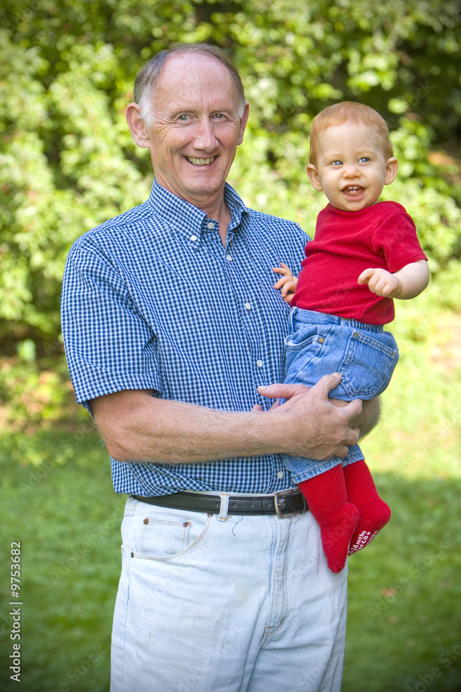 Grandfather holding happy grandson in sunny garden
