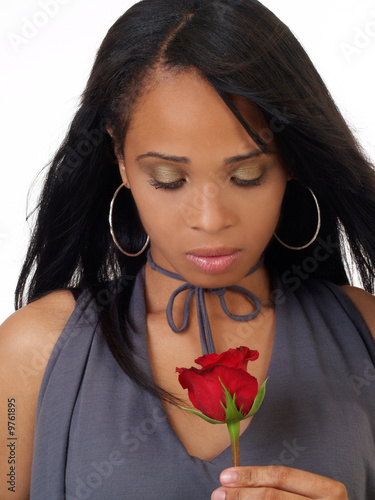 Young woman looking down at red rose african american