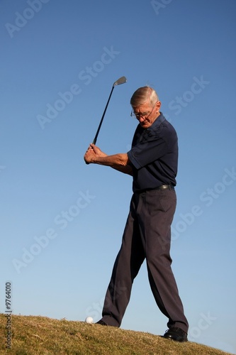 Senior golfing man about to strike the ball in the fairway