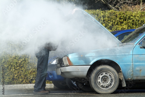 Man looking at a smoking engine in his car photo