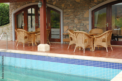 Cane chairs and table near swimming pool