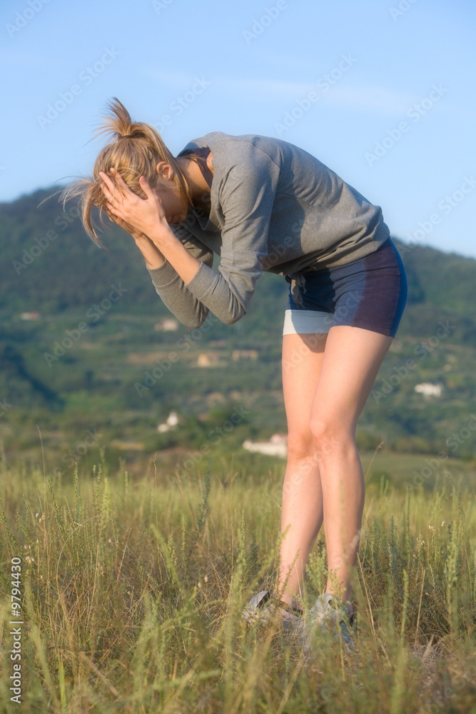 Young woman after sports in a hilly meadow Young woman after sports in a hilly meadow