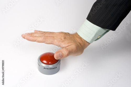A male hand actuating a panic button on a white surface.
