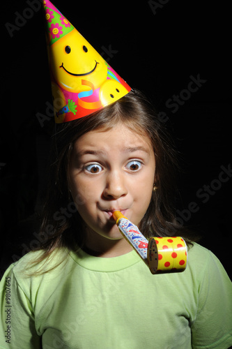 Portrait of a girl with party horn blowing in blowers