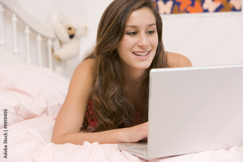 Teenage Girl Lying On Her Bed Using Laptop Teenage Girl Lying On Her Bed Using Laptop