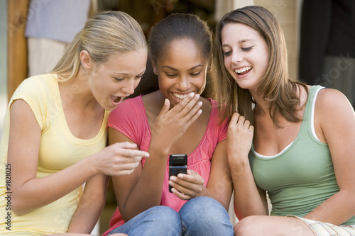 Teenage Girls Sitting Outside Playing With Mobile Phone