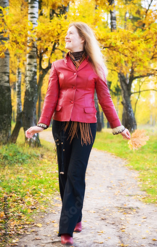 Young woman walking in a park. Autumn season.