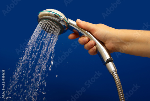 Hand holds a shower with drops of water