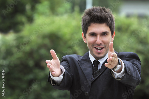 Young caucasian business man in a suite pointing at camera