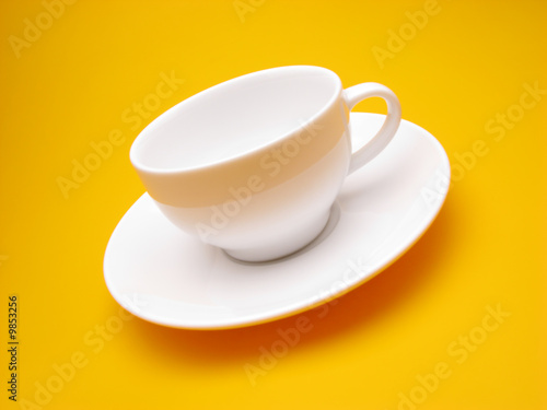 white cup and plate on  yellow background   close up