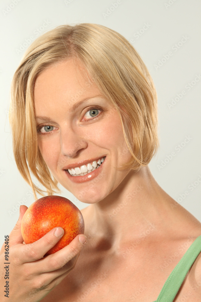Blond caucasian female holing a fresh nectarine.