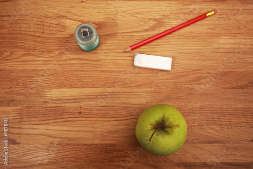 pencil, eraser, sharpener and apple lying on a school table