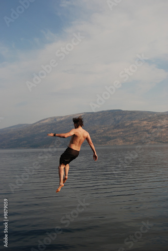 Man jumping from a jumping board into okanagan lake.