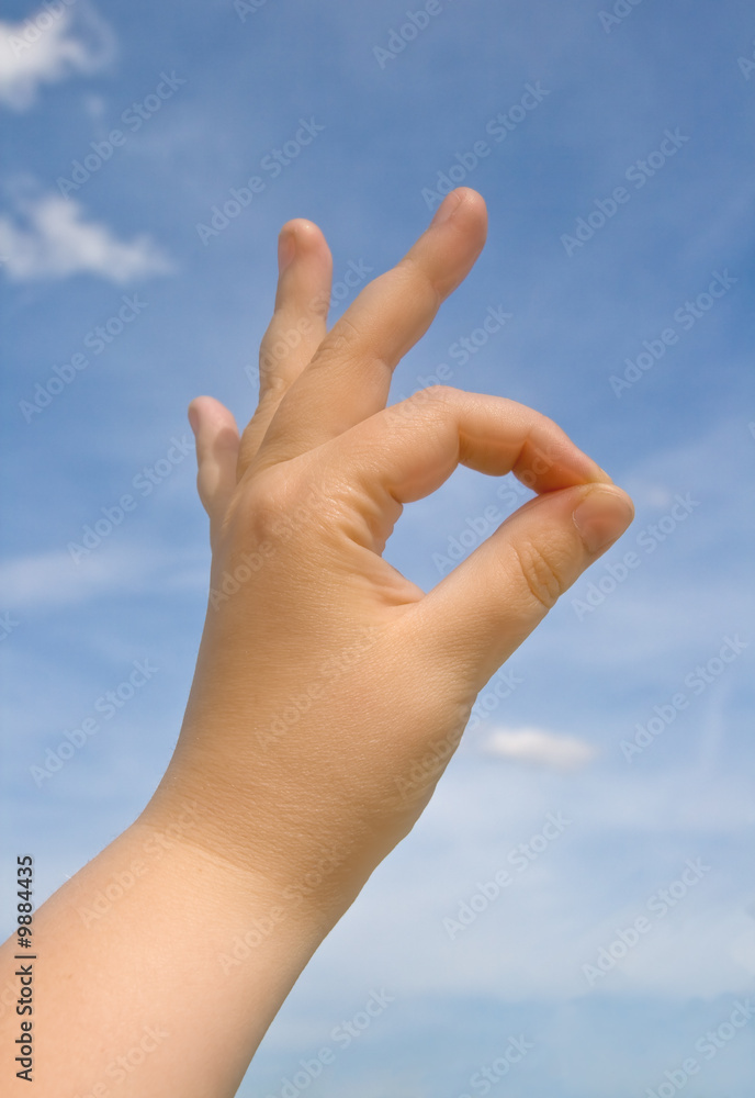 Human hand making OK sign against blue sky Human hand making OK sign against blue sky