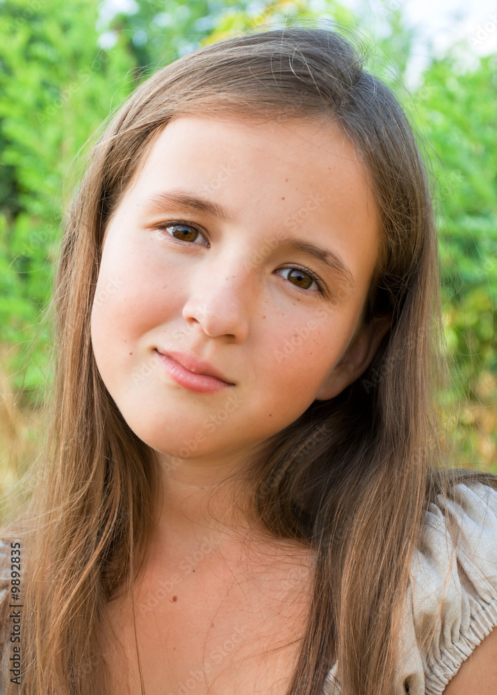 Portrait of young girl on green trees background Portrait of young girl on green trees background
