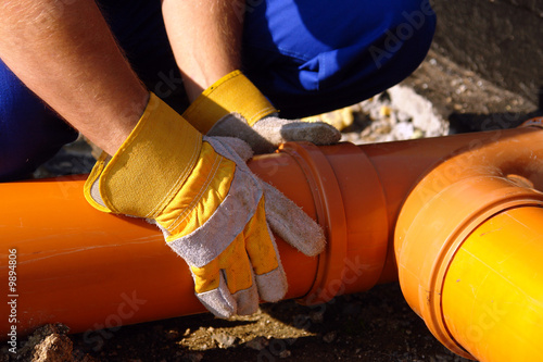 Closeup of plumber's hands assembling pvc sewage pipes