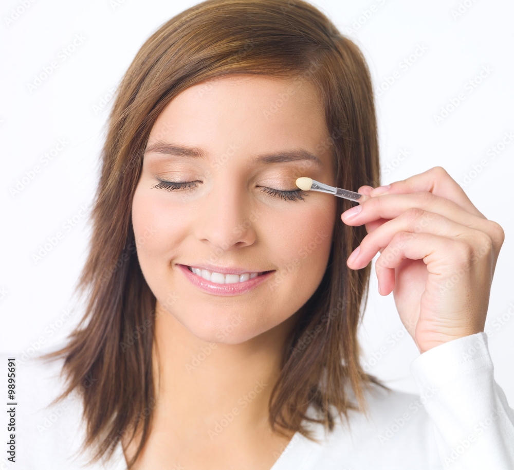 Portrait of beautiful young woman is doing her makeup